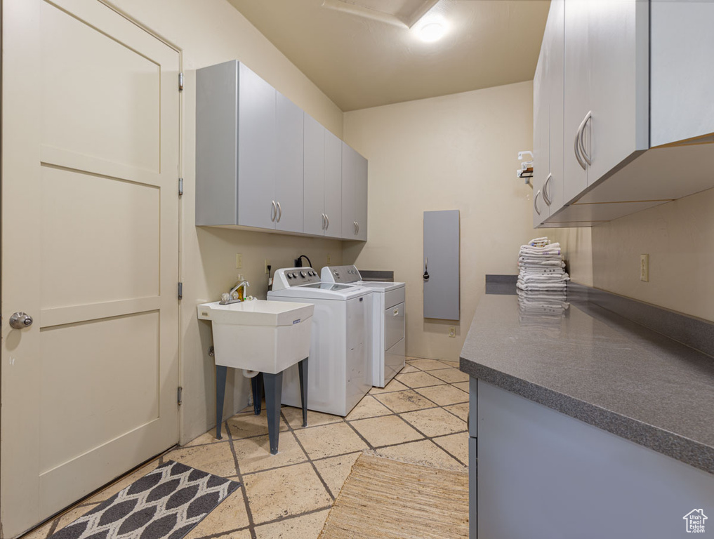 Clothes washing area with light tile floors, separate washer and dryer, and cabinets
