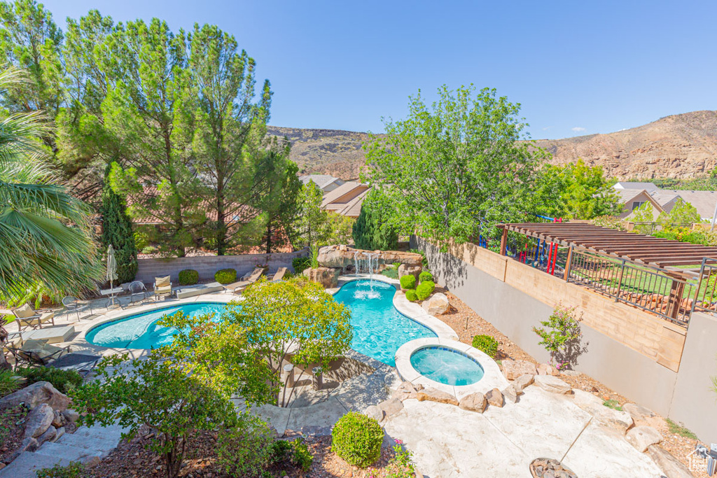 View of pool featuring a mountain view, pool water feature, a patio, and an in ground hot tub