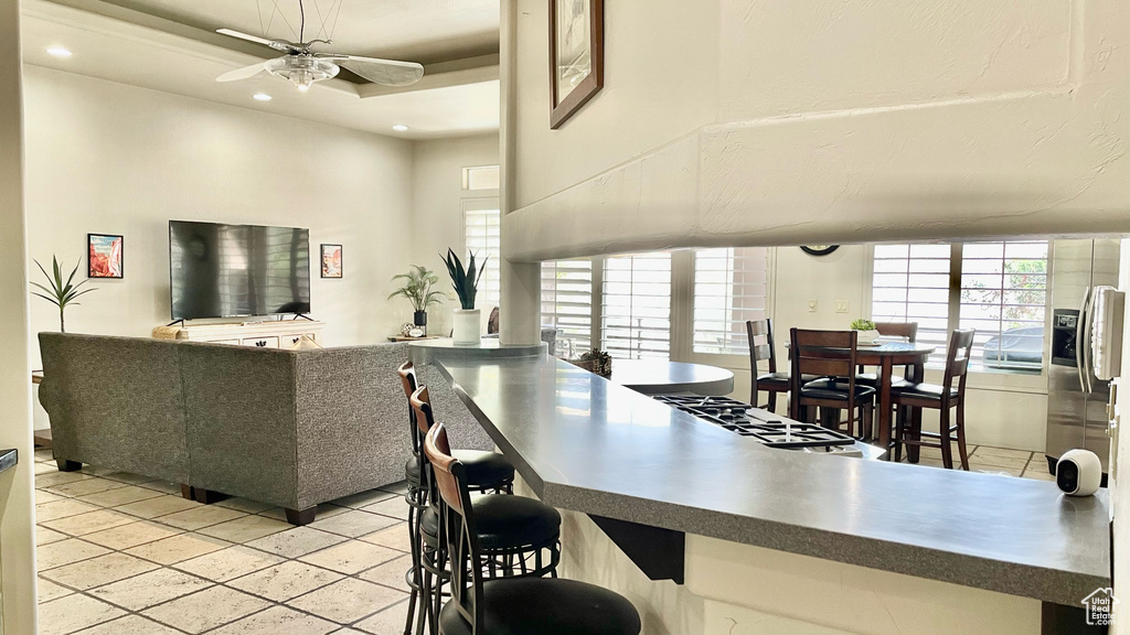 Kitchen with light tile flooring, a breakfast bar, and ceiling fan