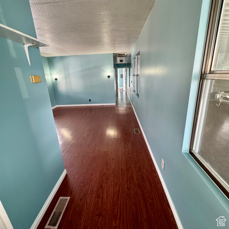 Corridor with dark hardwood / wood-style flooring and a textured ceiling