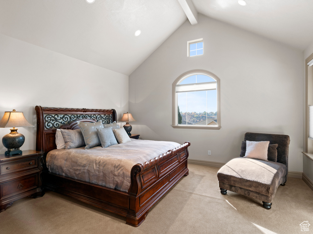 Bedroom with lofted ceiling with beams and light colored carpet