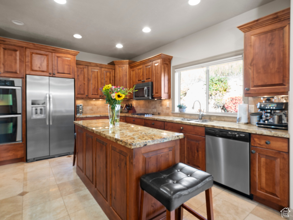 Kitchen featuring light tile floors, sink, stainless steel appliances, a kitchen island, and backsplash