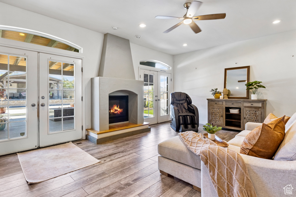 Living room featuring french doors, ceiling fan, hardwood / wood-style flooring, and a fireplace
