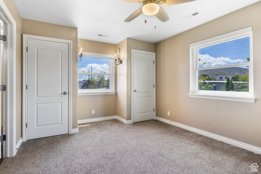 Unfurnished bedroom featuring light colored carpet, ceiling fan, and multiple windows