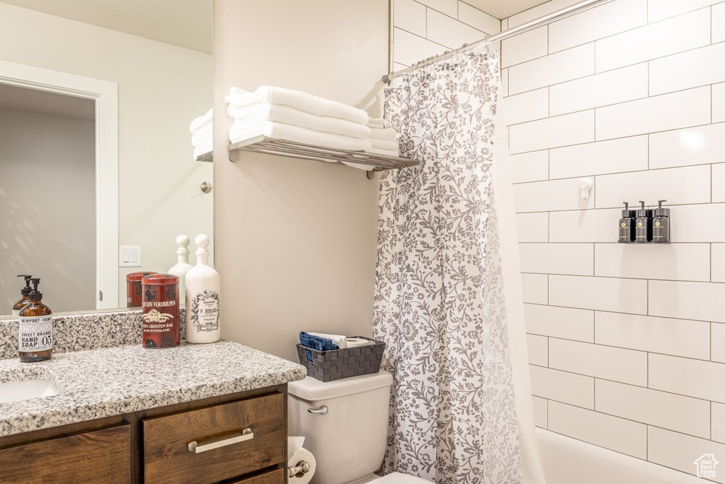 Full bathroom with vanity, shower / bath combination with curtain, and toilet