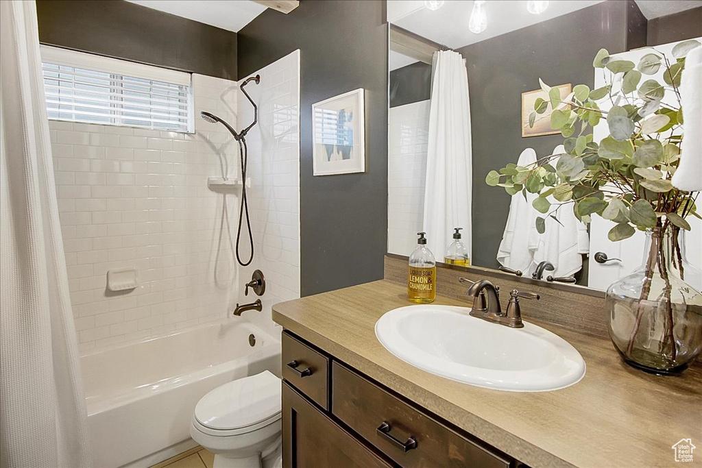 Full bathroom featuring large vanity, shower / tub combo with curtain, and toilet