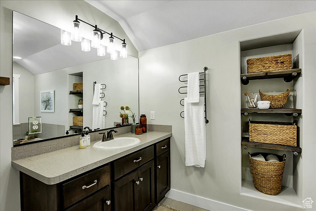 Bathroom with vaulted ceiling, oversized vanity, and tile flooring