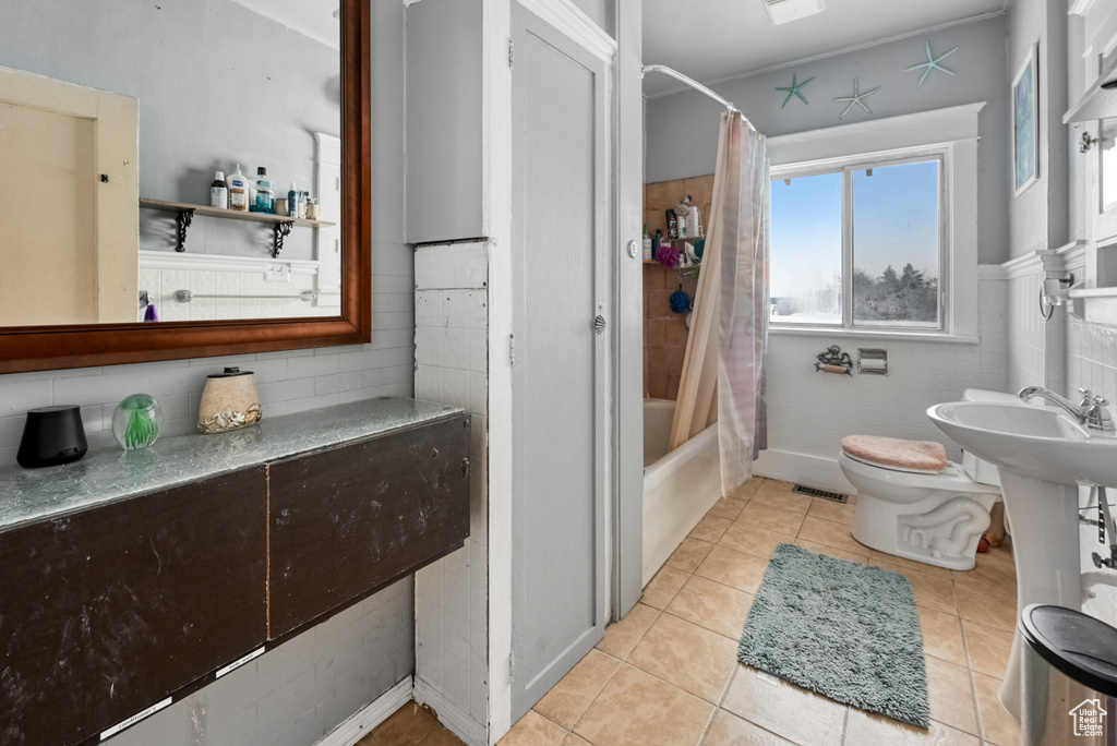 Bathroom with toilet, shower / tub combo, and tile flooring