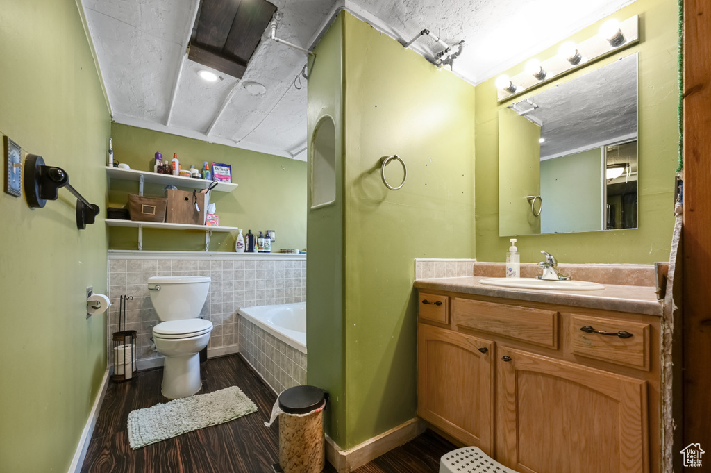 Bathroom with ornamental molding, vanity, toilet, tile walls, and a bathtub