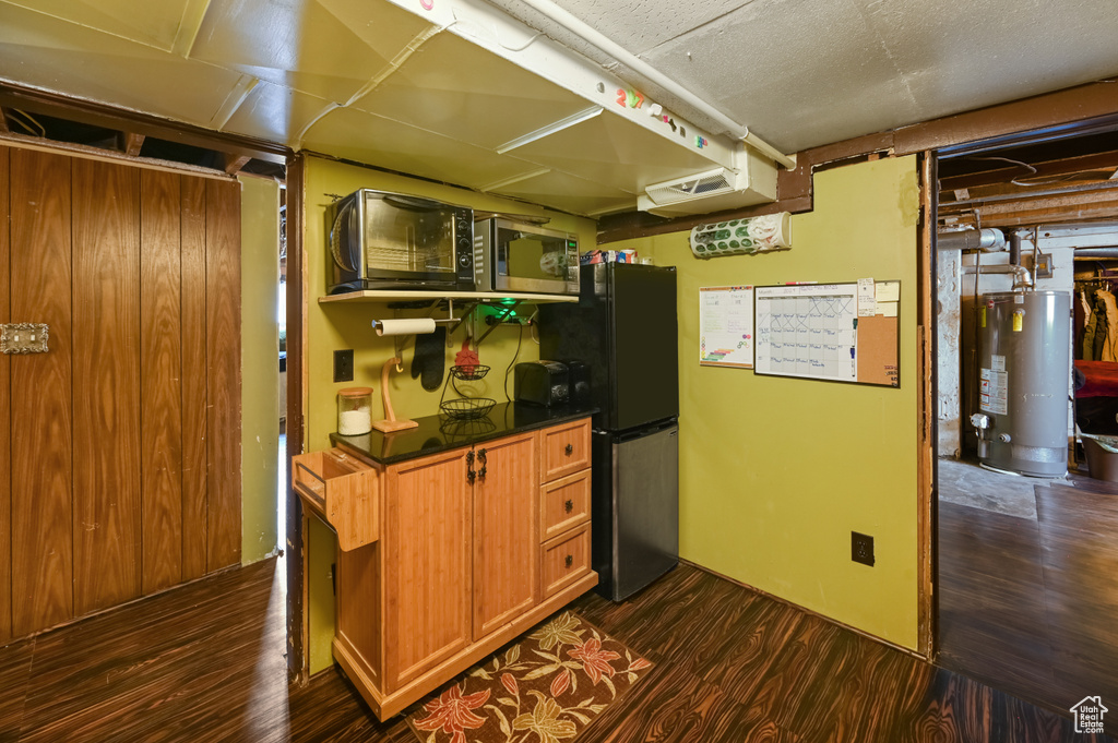Interior space with dark hardwood / wood-style floors, black fridge, water heater, and stainless steel microwave
