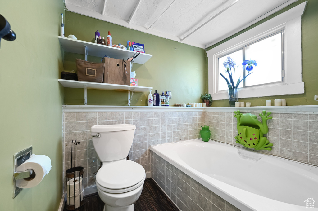 Bathroom featuring hardwood / wood-style floors, tiled bath, and toilet