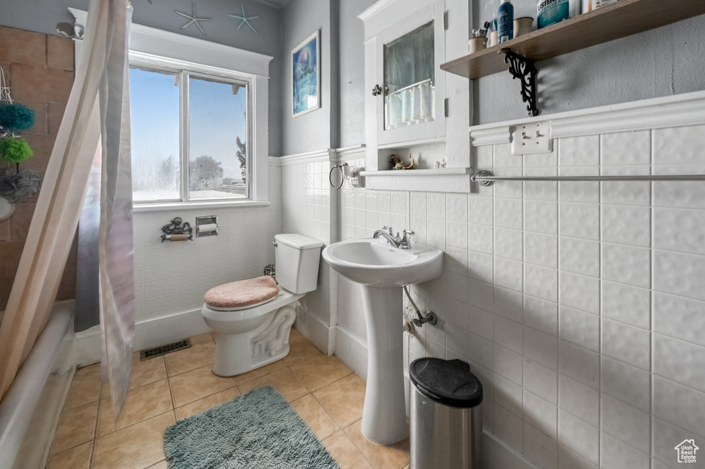 Bathroom featuring tile walls, tile flooring, and toilet