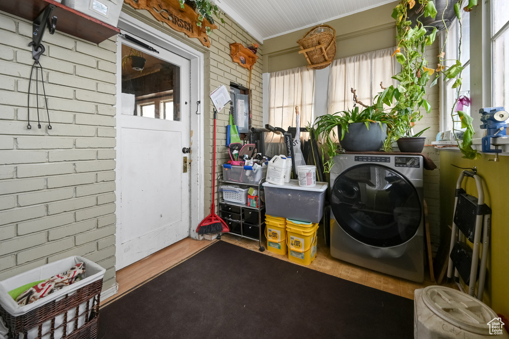Clothes washing area featuring washer / dryer, a wealth of natural light, dark hardwood / wood-style floors, and ornamental molding