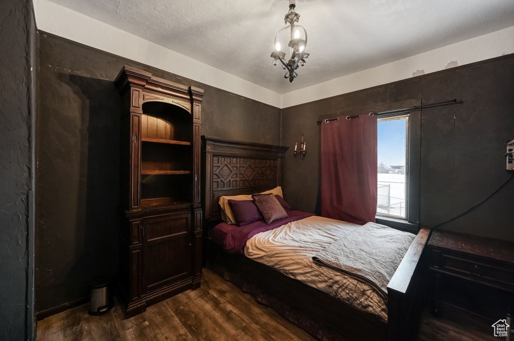 Bedroom with an inviting chandelier and dark hardwood / wood-style flooring