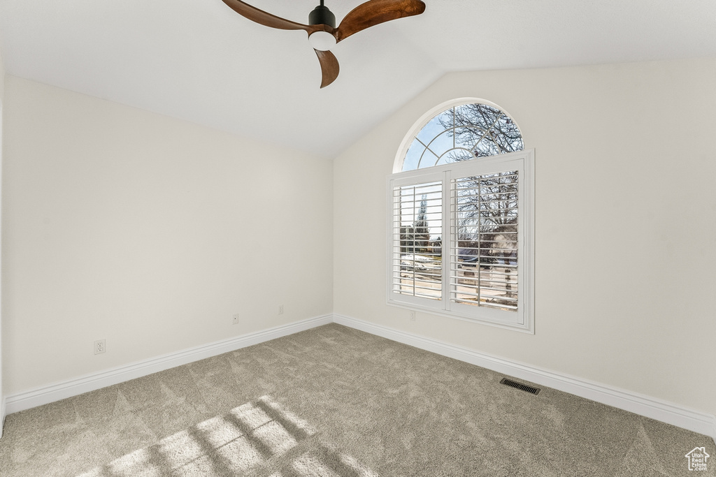 Empty room with ceiling fan, light colored carpet, and lofted ceiling