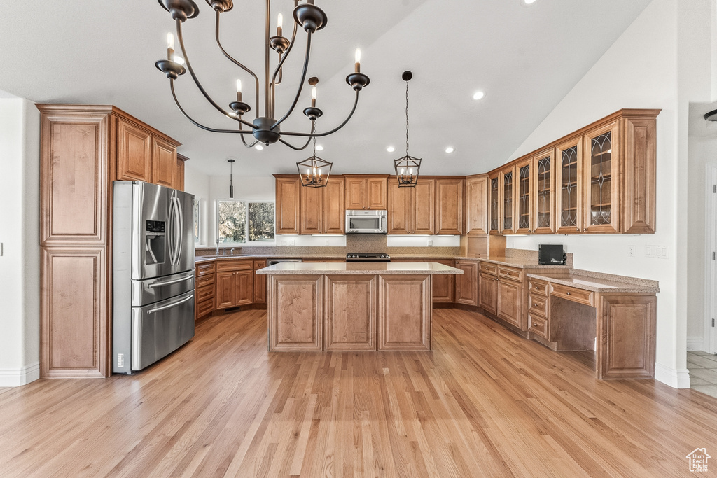 Kitchen featuring light hardwood / wood-style flooring, a center island, appliances with stainless steel finishes, and hanging light fixtures