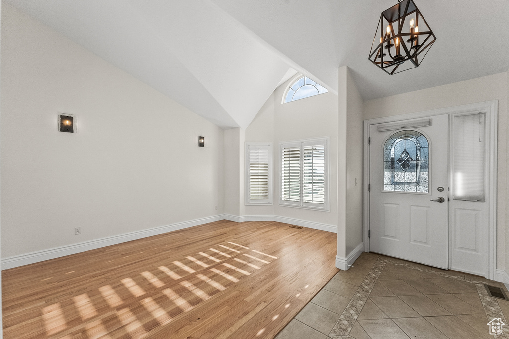 Entrance foyer with light tile flooring, high vaulted ceiling, and a chandelier