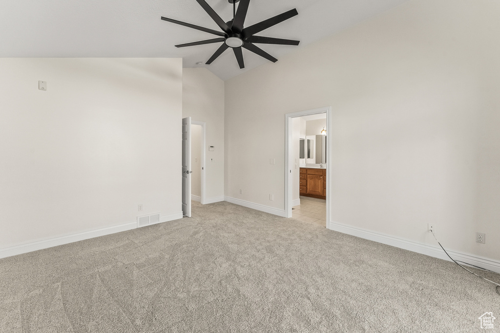 Unfurnished bedroom featuring ensuite bathroom, ceiling fan, light colored carpet, and high vaulted ceiling