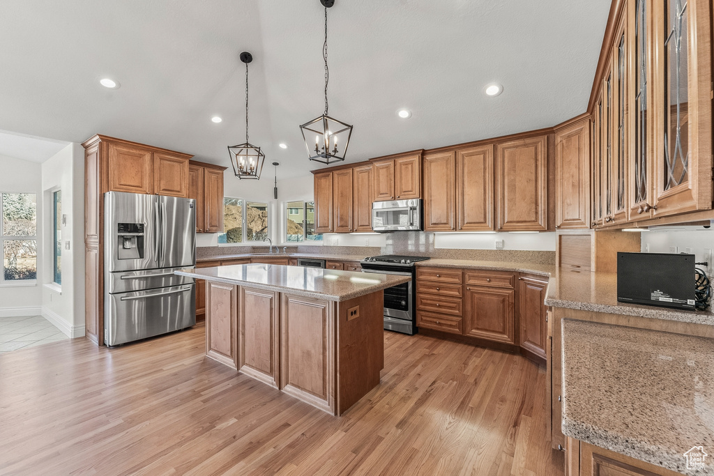 Kitchen with a notable chandelier, a kitchen island, appliances with stainless steel finishes, sink, and decorative light fixtures