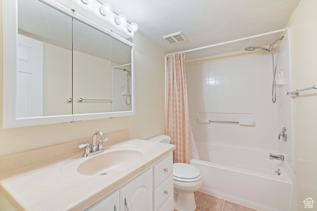 Full bathroom featuring a textured ceiling, vanity, shower / bath combo, toilet, and tile flooring