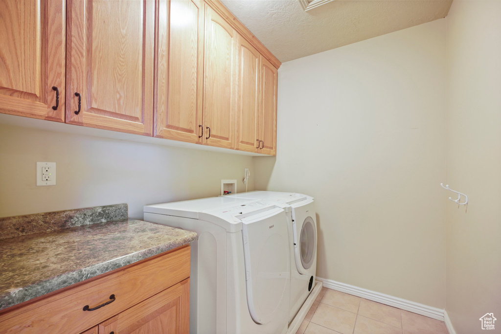 Laundry room featuring cabinets, washer hookup, light tile floors, and washing machine and clothes dryer