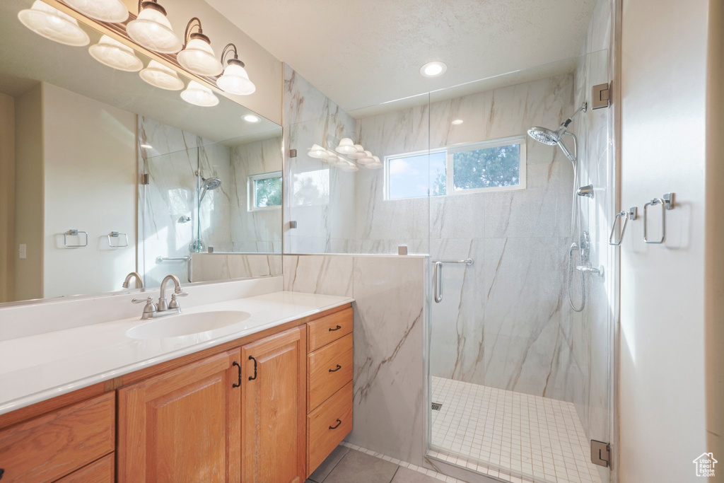 Bathroom with a shower with shower door, oversized vanity, and tile flooring