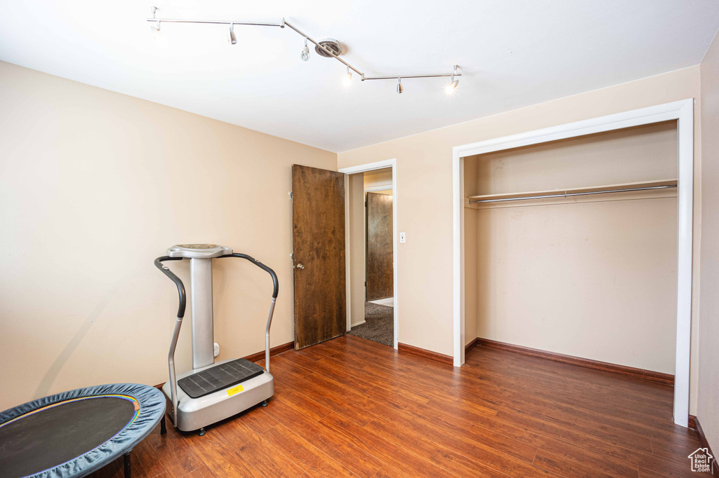 Workout room with rail lighting and dark hardwood / wood-style flooring