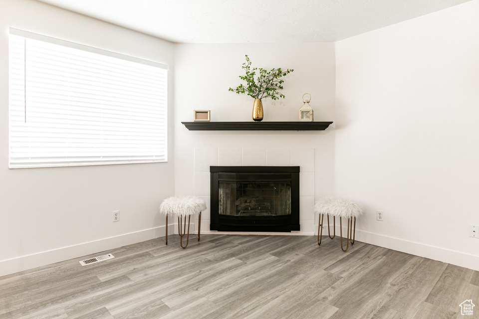 Unfurnished room featuring light hardwood / wood-style floors and a tile fireplace