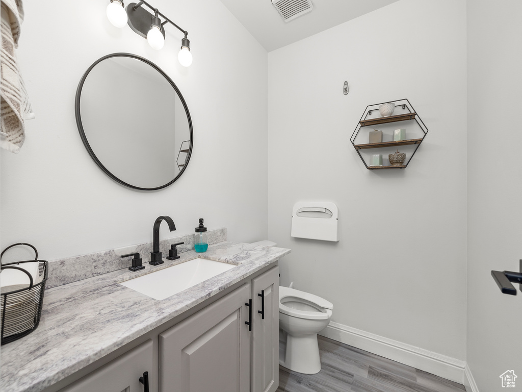 Bathroom featuring toilet, large vanity, and hardwood / wood-style flooring