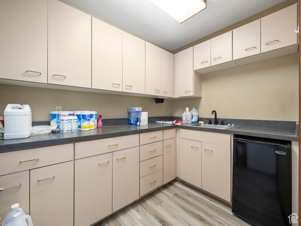 Kitchen with white cabinetry, light hardwood / wood-style floors, sink, and black dishwasher