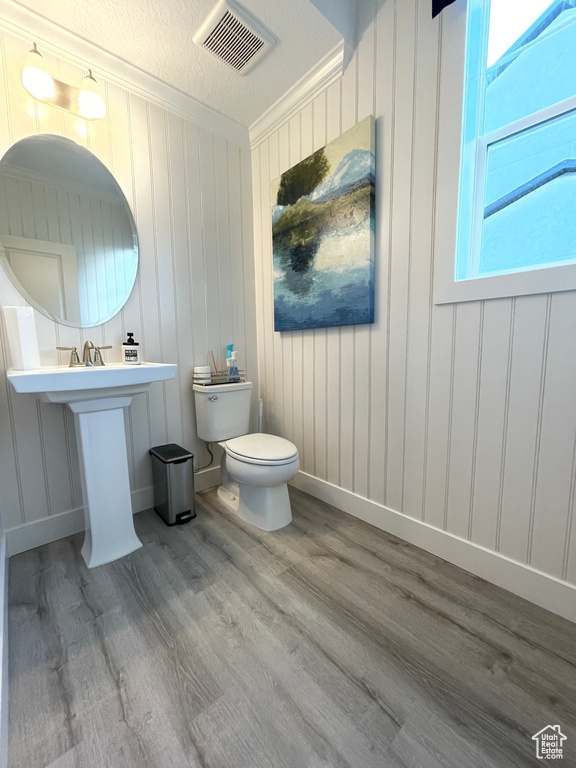 Bathroom featuring toilet, hardwood / wood-style floors, a textured ceiling, and crown molding