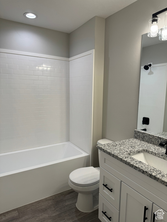 Full bathroom with tiled shower / bath, toilet, large vanity, and hardwood / wood-style floors