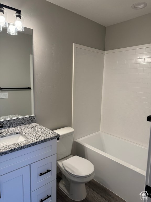 Full bathroom featuring  shower combination, toilet, vanity with extensive cabinet space, and hardwood / wood-style flooring
