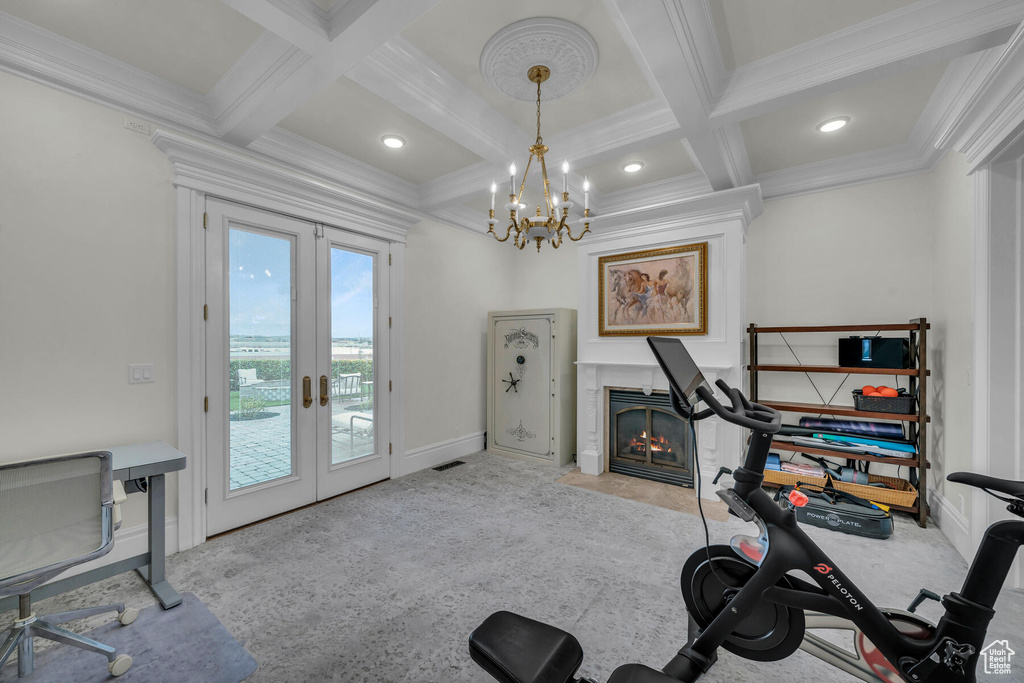 Exercise area featuring an inviting chandelier, coffered ceiling, crown molding, and french doors
