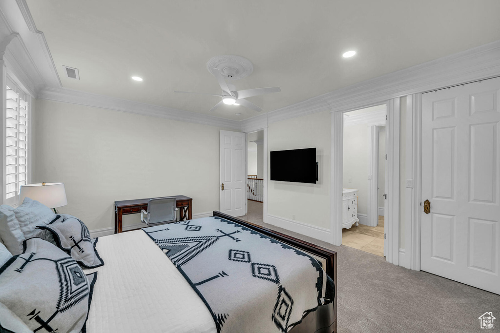 Carpeted bedroom featuring connected bathroom, ceiling fan, and ornamental molding