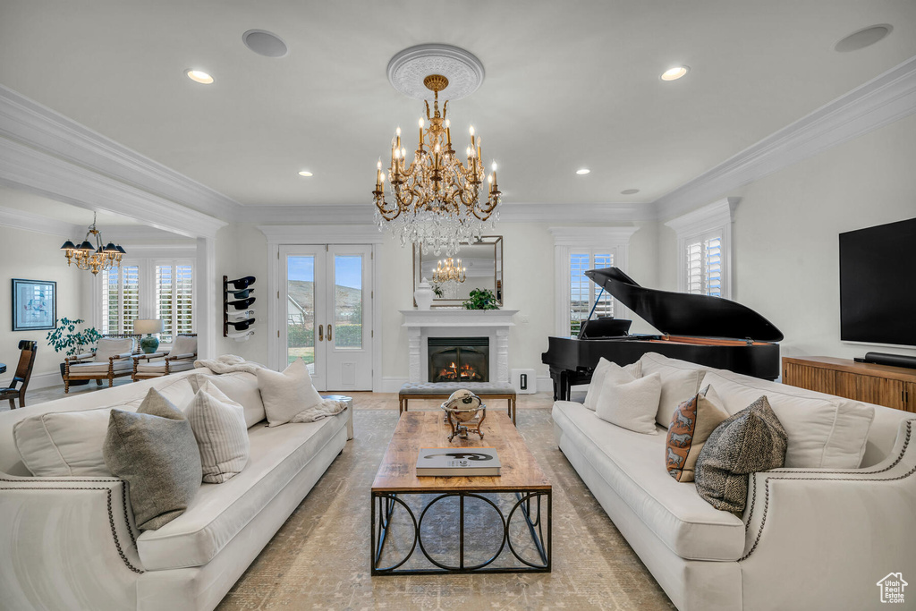Living room with plenty of natural light, crown molding, and a notable chandelier