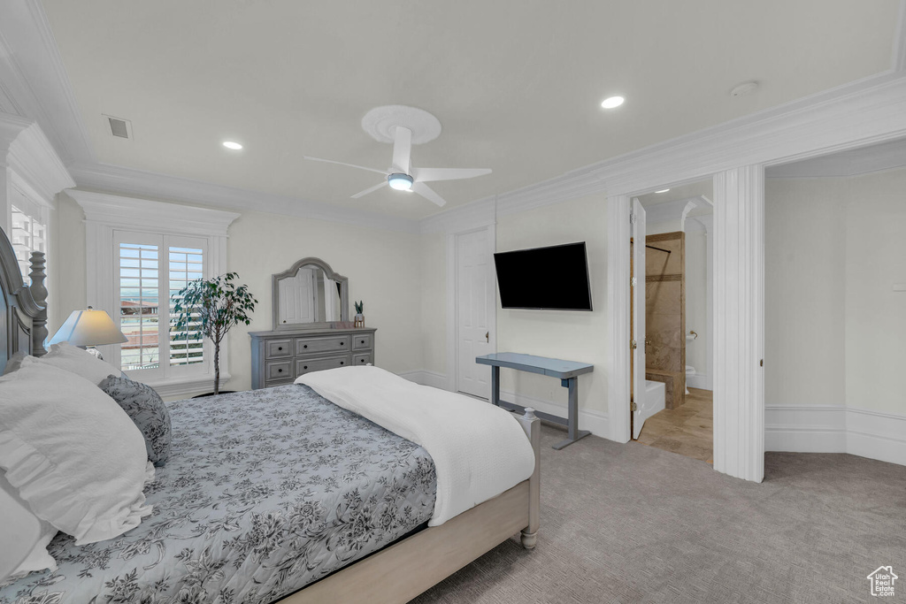 Bedroom with ceiling fan, light colored carpet, ensuite bathroom, and ornamental molding