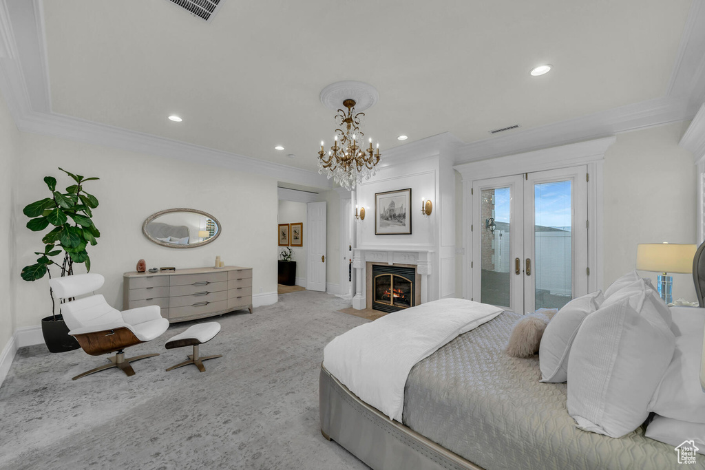Bedroom featuring an inviting chandelier, ornamental molding, a fireplace, access to outside, and light colored carpet