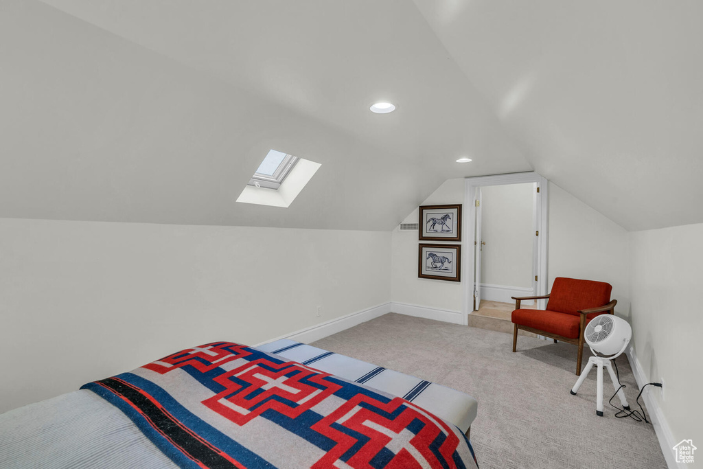 Bedroom featuring light carpet and vaulted ceiling with skylight