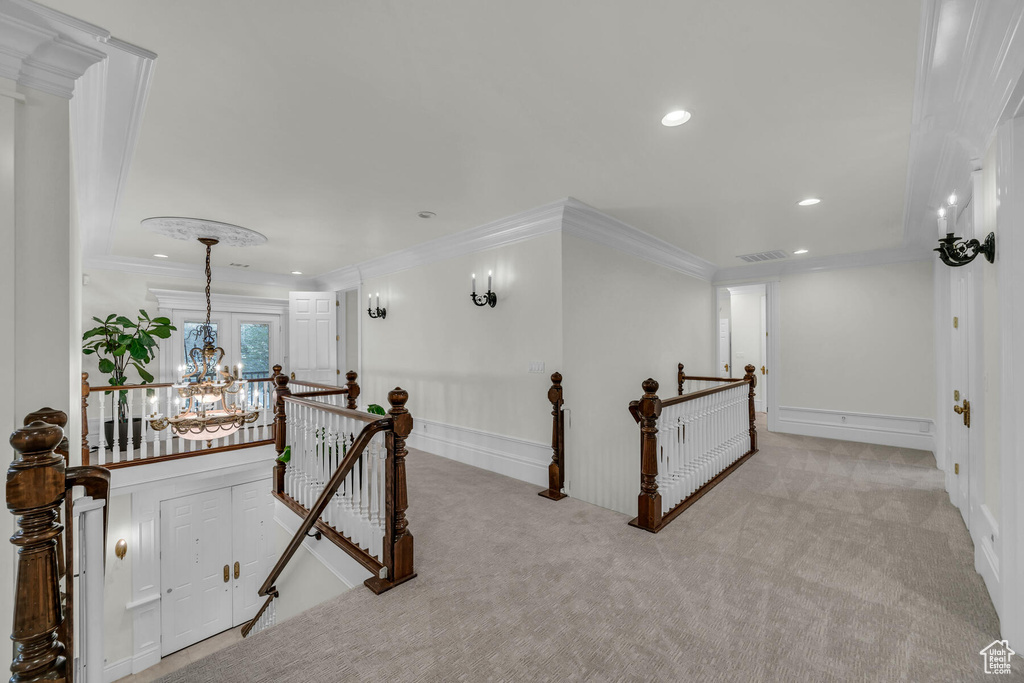 Hall featuring crown molding, light carpet, and a notable chandelier
