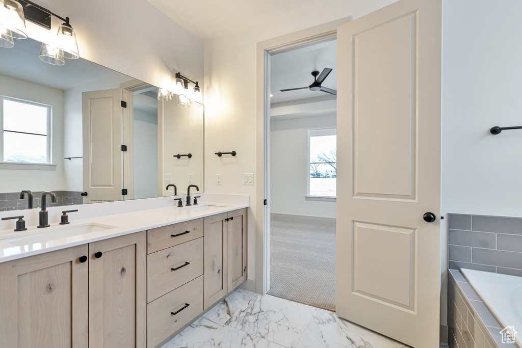 Bathroom with a wealth of natural light, double sink vanity, tile flooring, and tiled bath