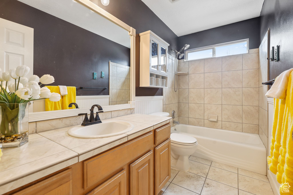 Full bathroom with large vanity, tiled shower / bath, tile flooring, and toilet