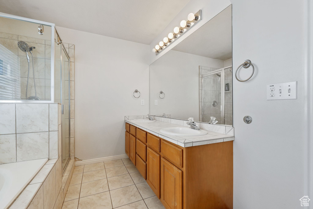 Bathroom featuring walk in shower, double vanity, and tile floors