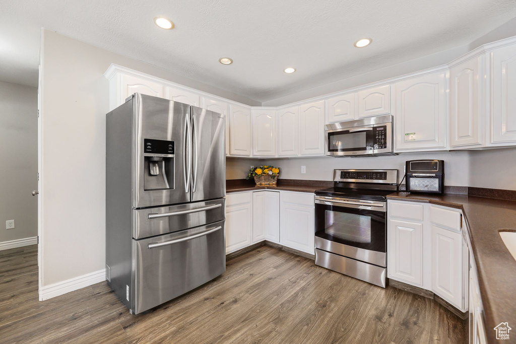 Kitchen with white cabinets, dark hardwood / wood-style floors, and stainless steel appliances