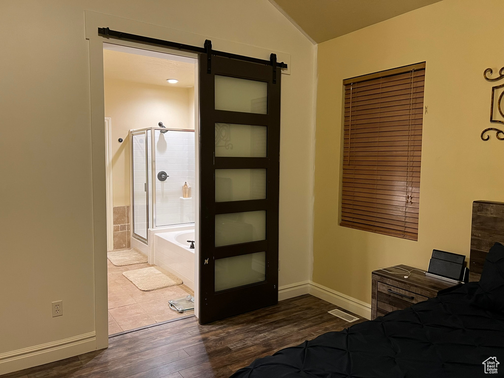 Bedroom featuring dark hardwood / wood-style floors, connected bathroom, and a barn door