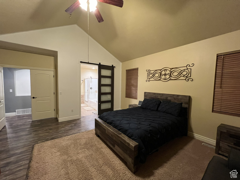 Bedroom with a barn door, dark hardwood / wood-style floors, connected bathroom, and ceiling fan