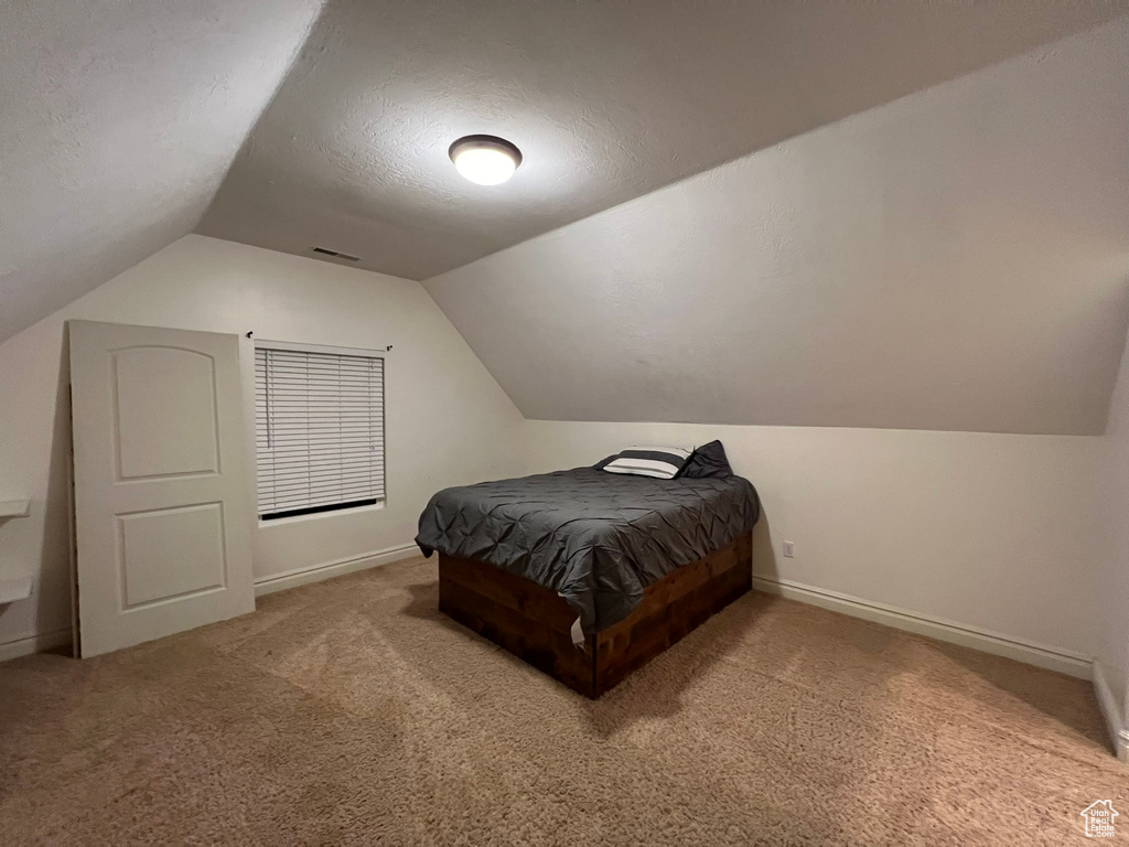 Carpeted bedroom featuring vaulted ceiling