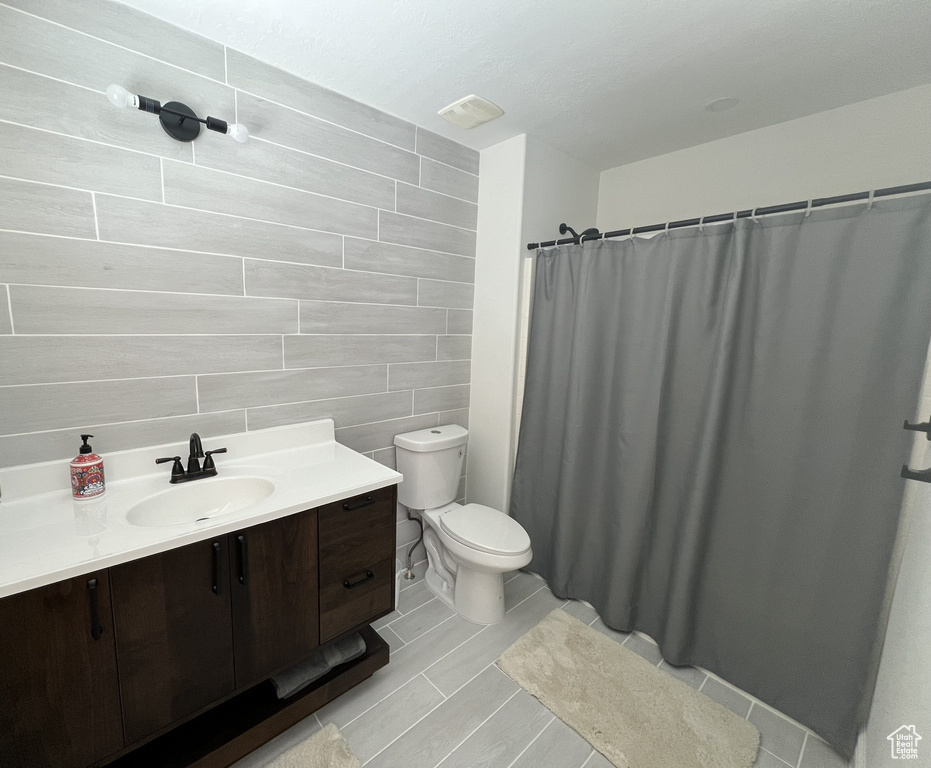 Bathroom with vanity, toilet, tile walls, and tile floors