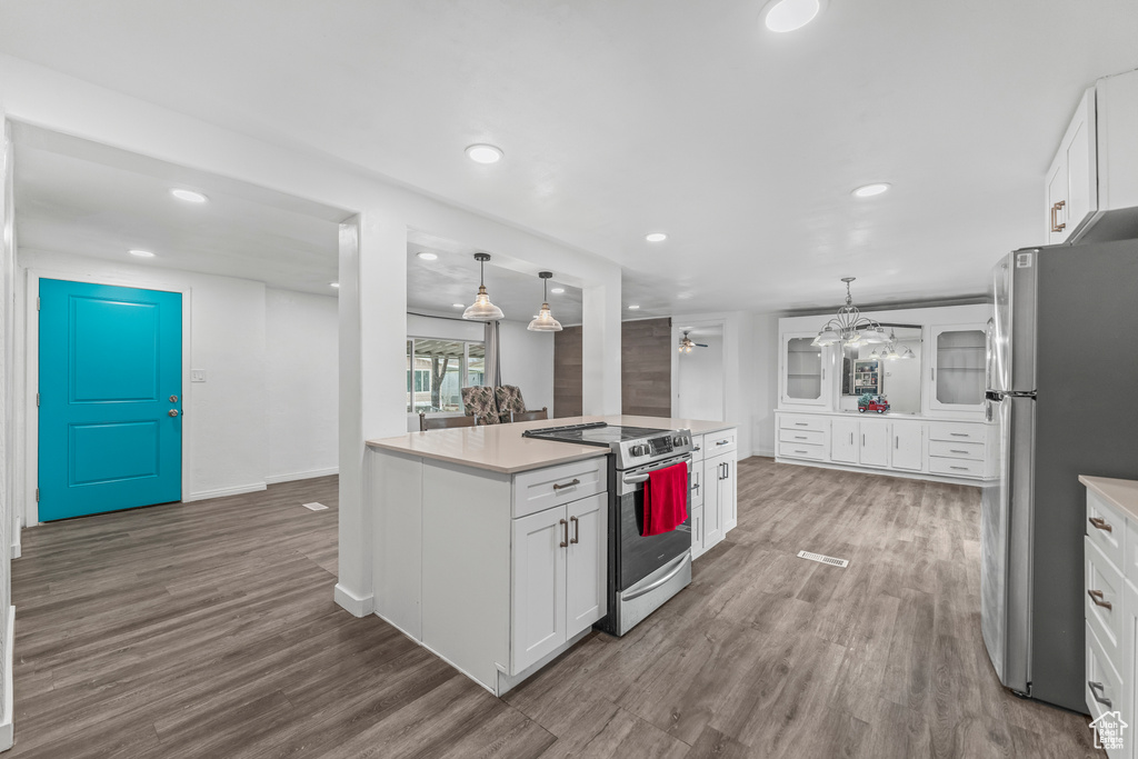 Kitchen with white cabinets, hardwood / wood-style flooring, decorative light fixtures, a chandelier, and appliances with stainless steel finishes