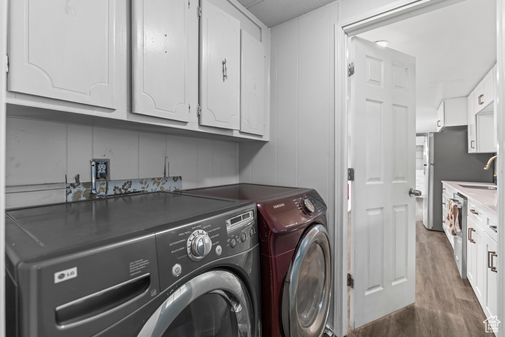 Laundry area with cabinets, sink, dark wood-type flooring, and washing machine and clothes dryer